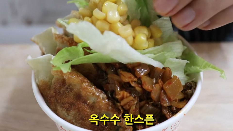 컵에 밥과 만두, 김치, 양상추, 옥수수를 올리는 장면