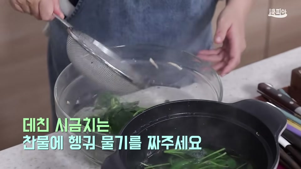 데친 시금치를 찬물에 헹궈 물기를 짜는 장면