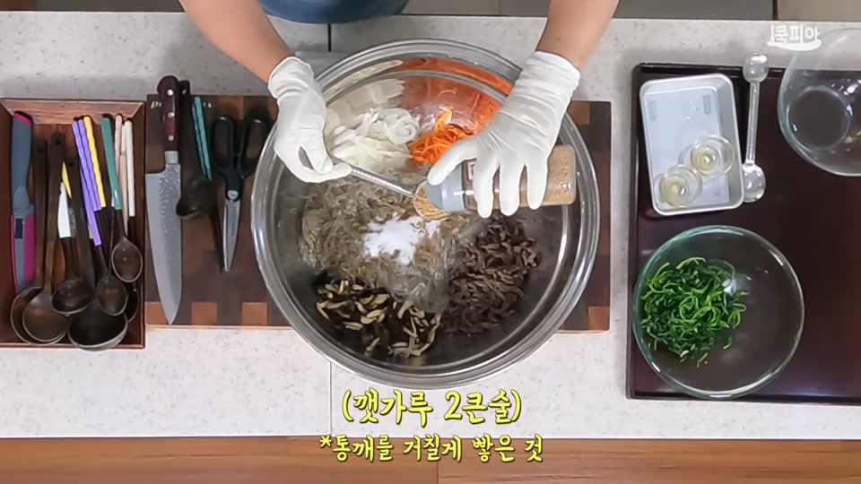큰 볼에 당면과 재료를 넣고 양념하는 장면